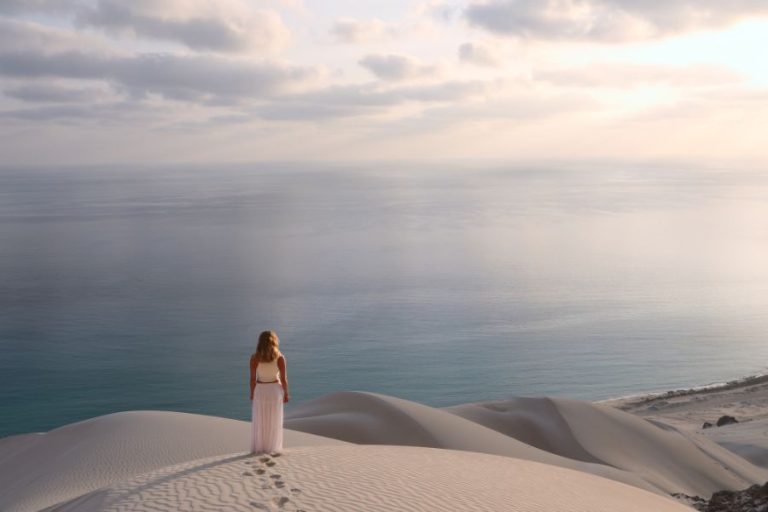 Woman standing on top of a sand dune. Tourists are safe in Socotra